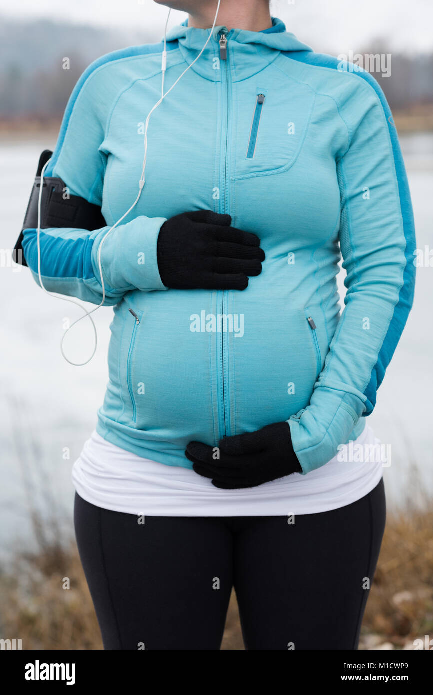 Schwangere Frau ihren Bauch berühren im Park Stockfoto
