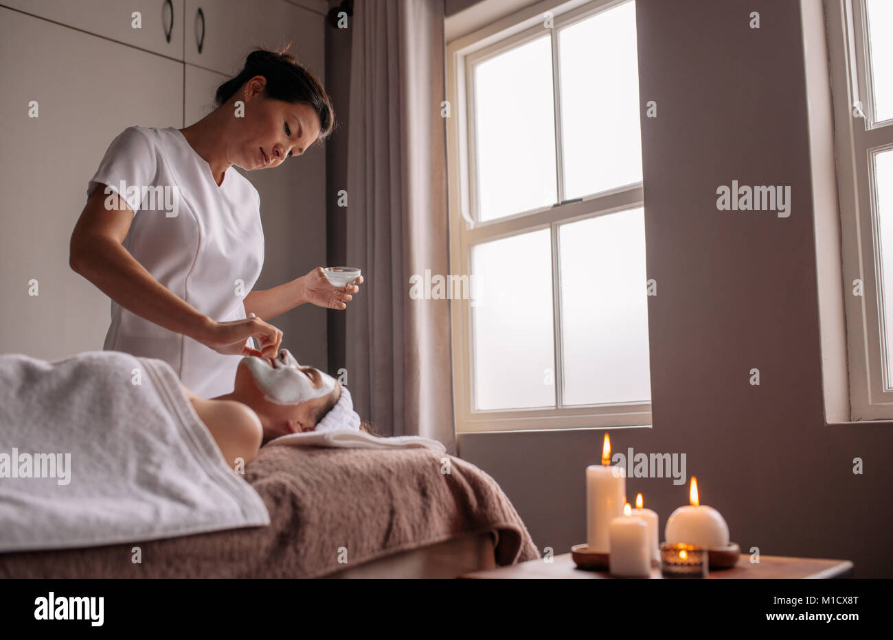 Frauen, die eine Gesichtsmaske Behandlung im Beauty Spa durch Therapeuten. Erfahrene Kosmetikerin, die Gesichtsmaske auf weibliche Gesicht. Stockfoto