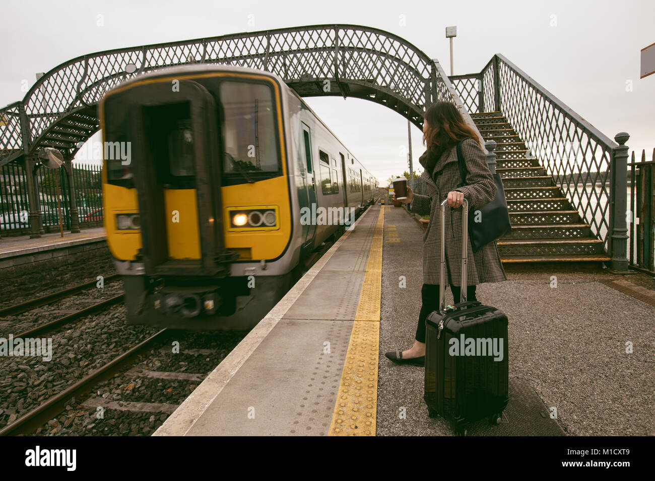 Frau warten auf den Zug mit Gepäck Stockfoto