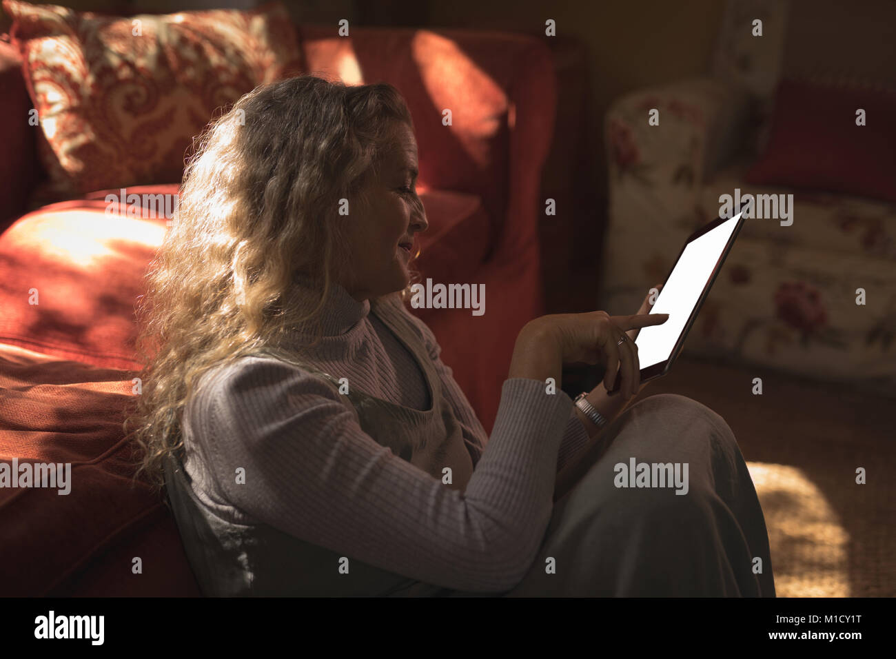 Reife Frau sitzt auf dem Boden und über Ihr Tablet Stockfoto