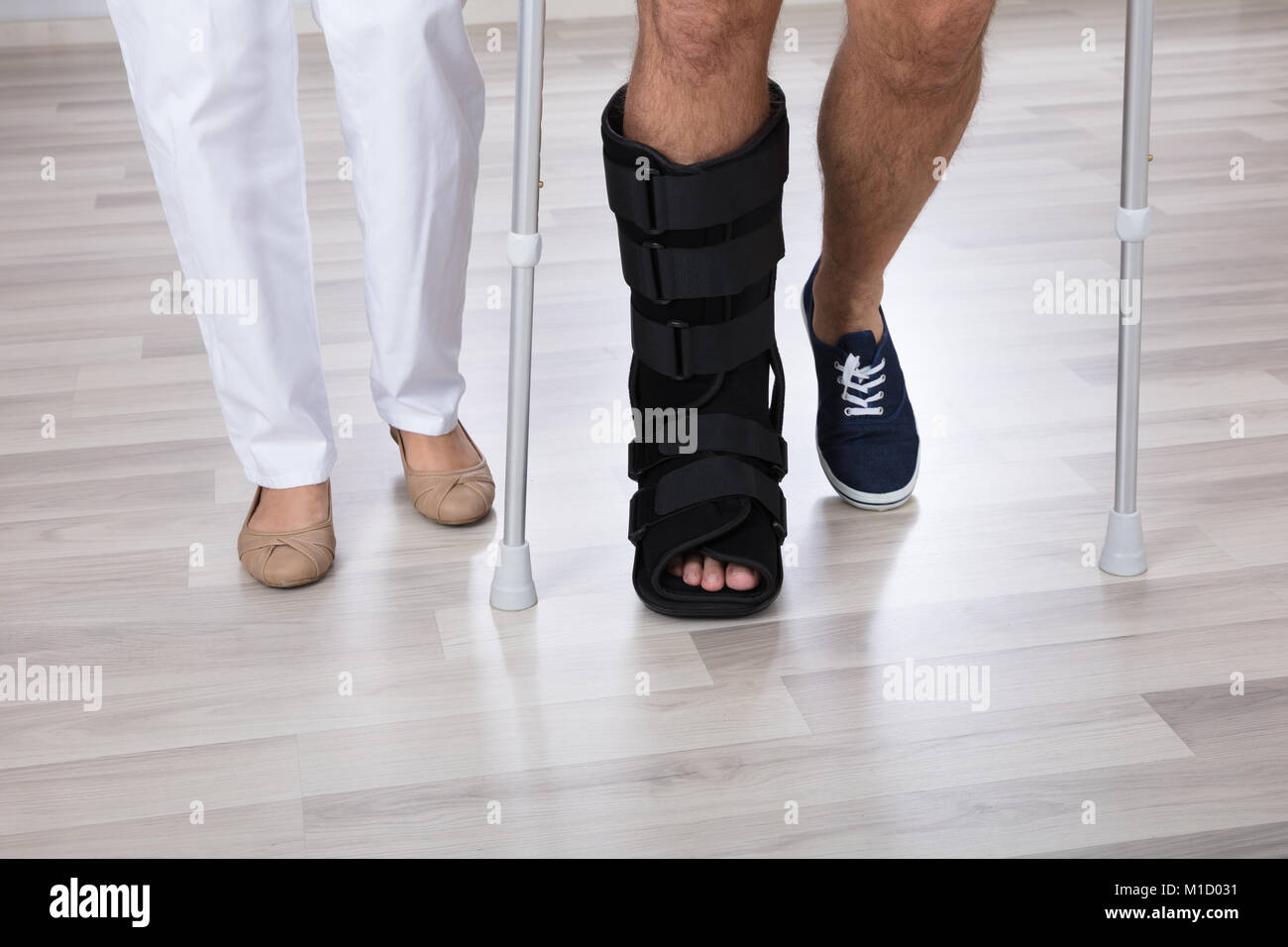 Niedrige Schnittansicht des Physiotherapeuten und verletzte Person's Bein tragen zu Fuß Bandage Stockfoto