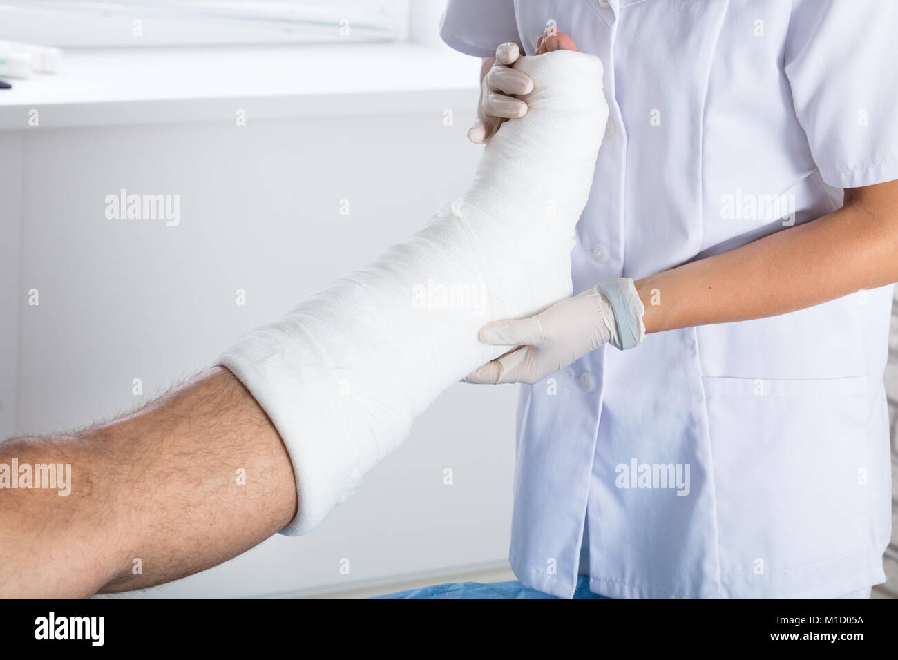 Nahaufnahme von einer Ärztin Untersuchen verletzte Person's Bein in der Klinik Stockfoto