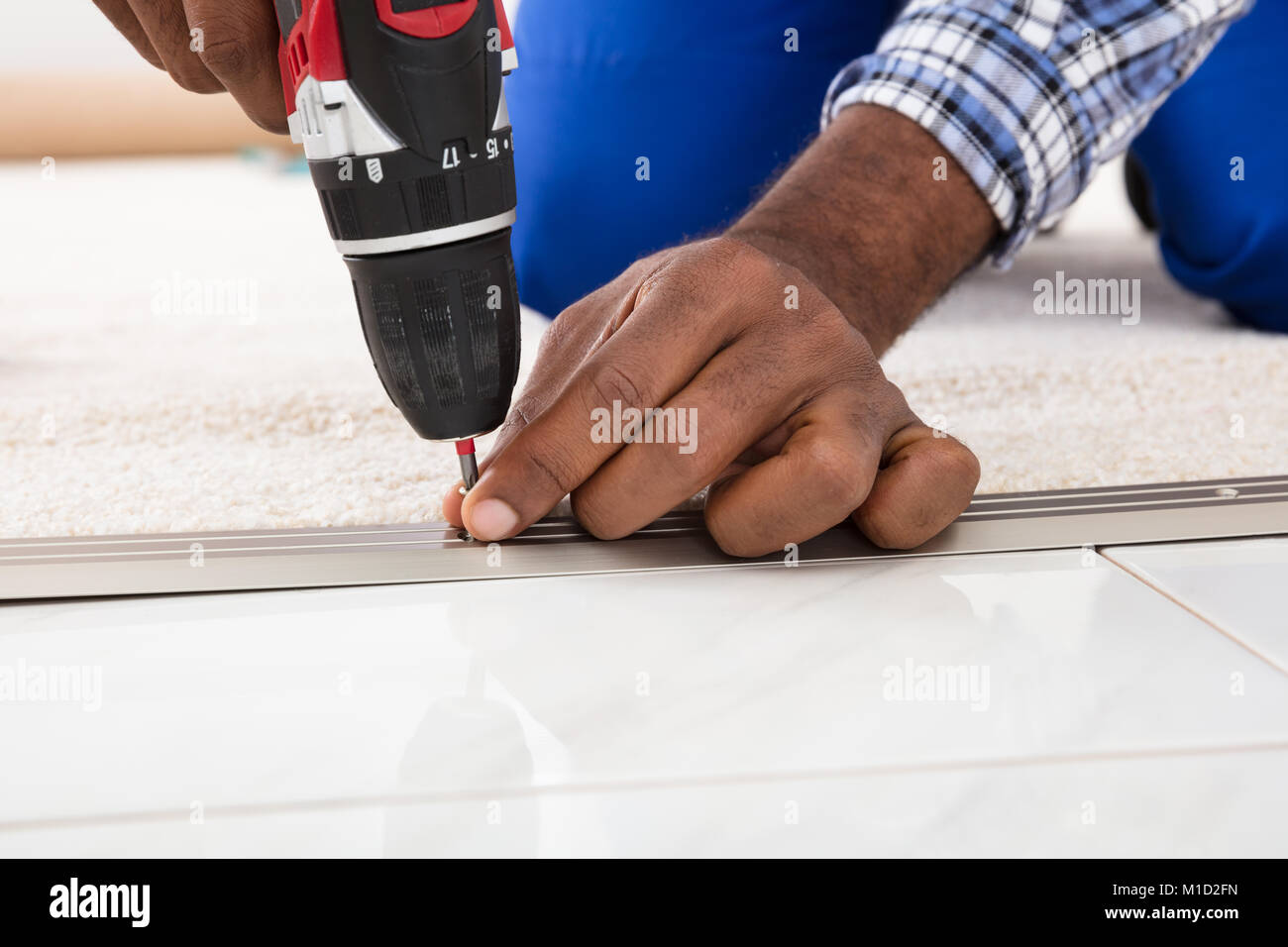 Person Hand Einbau Teppich auf dem Boden mit drahtlosen Schraubendreher Stockfoto