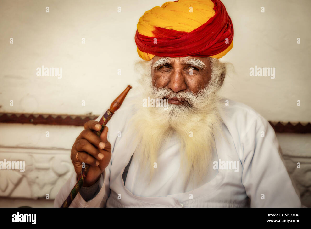 Alter Mann in traditionellen Rajasthani Kleid und bunten turban Rauchen einer Wasserpfeife an Mehrangarh Fort. Stockfoto