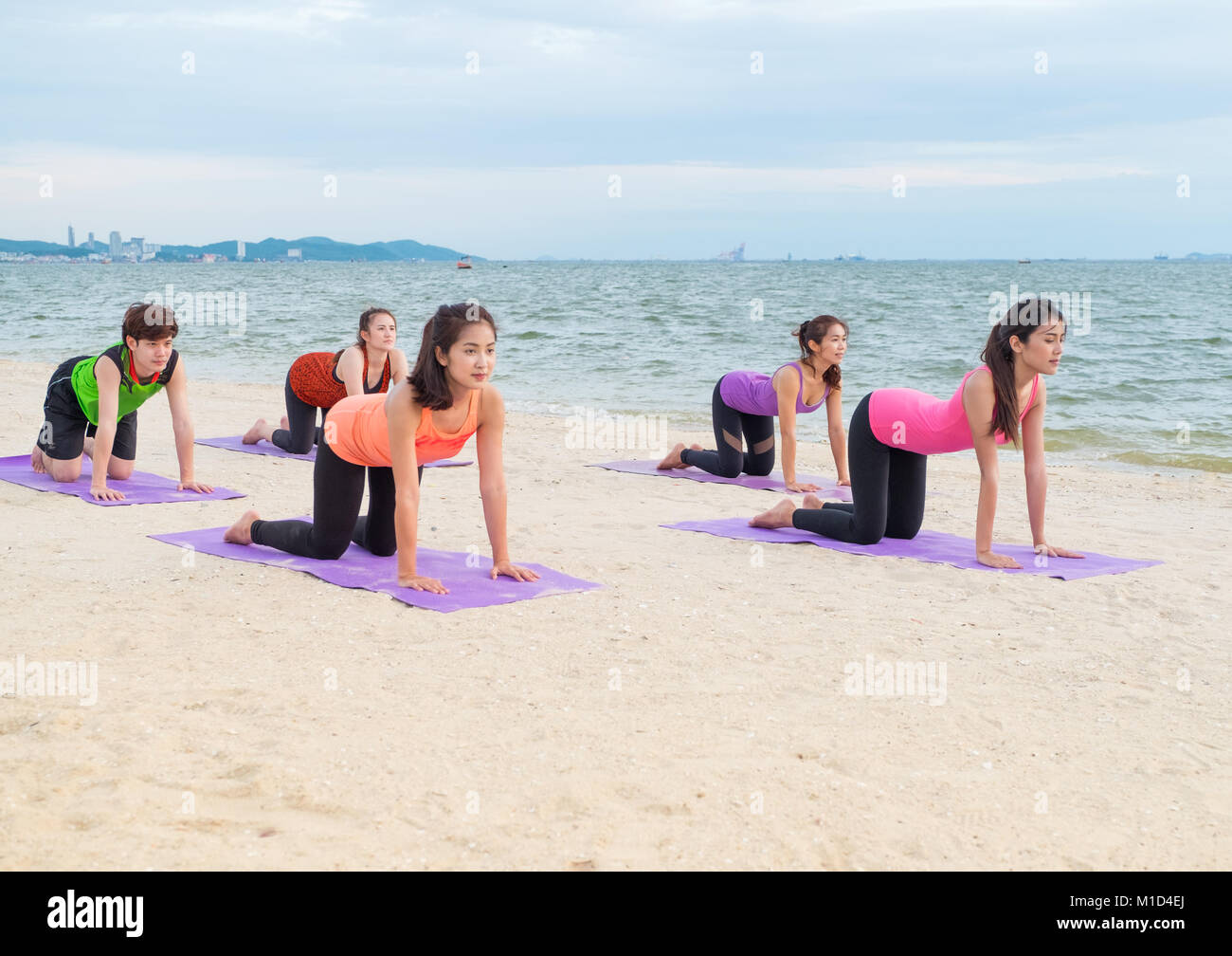 Yoga am Meer Strand im Sonnenuntergang am Abend, einer Gruppe von Menschen, die Katze wirft mit Clam emotion am Strand entspannen, Meditation, Wellness und gesunden Balan Stockfoto