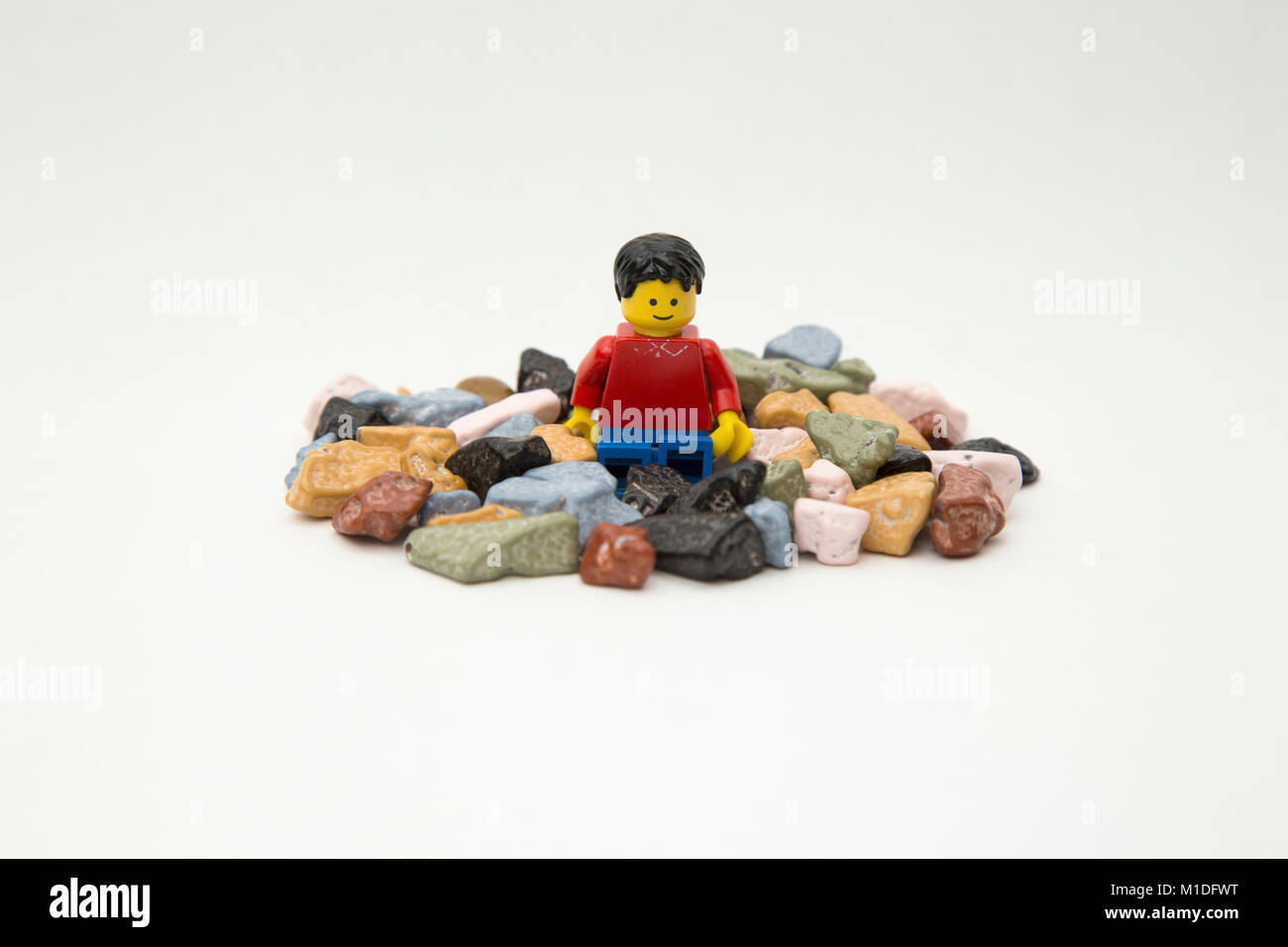 Larry der Lego Kerl sitzt in einem Haufen von Schokolade Felsen. Stockfoto