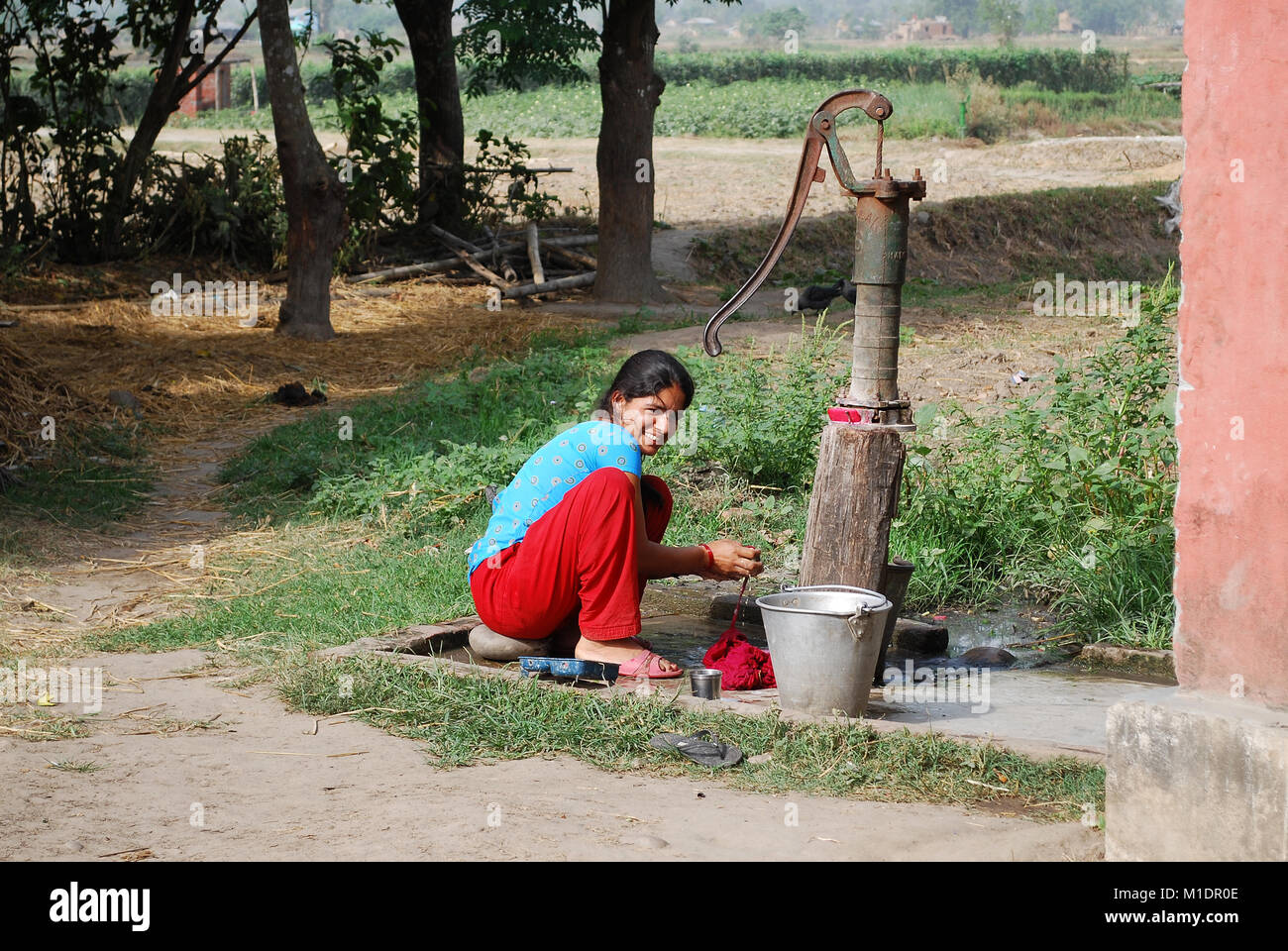 Frau Waschen der Kleidung an der Wasserpumpe in einem ländlichen Gebiet von Nepal an der Grenze zu Indien Stockfoto