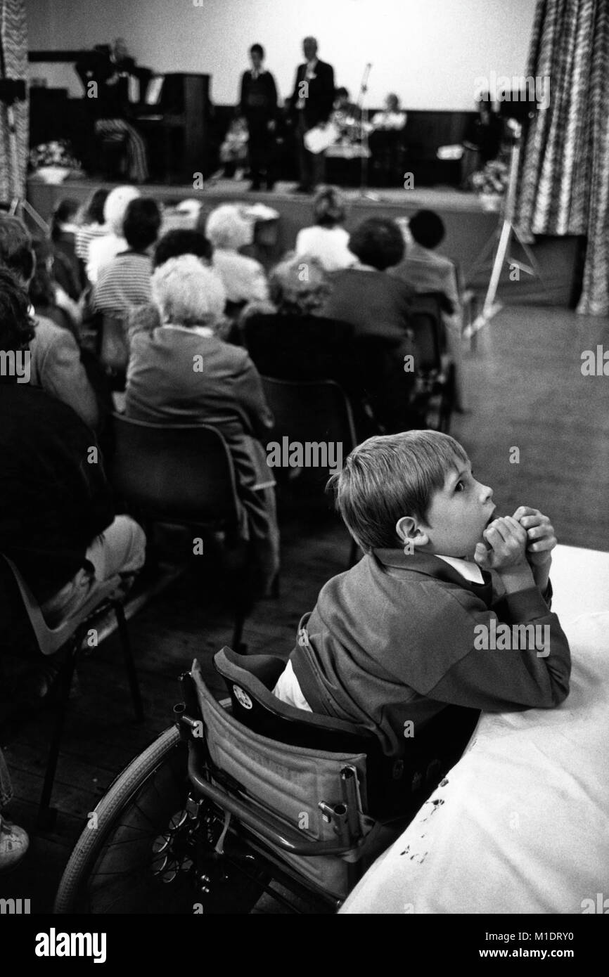 Junge Junge im Rollstuhl auf einer Seite des Publikums bei kleinen Eisteddfod in Village Hall an Trefeglwys Powys Wales UK Stockfoto