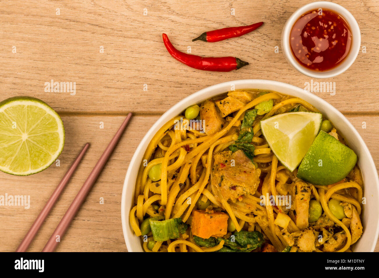 Gelbes Thai Chicken Curry mit Nudeln und Kartoffel auf hellem Holztisch Hintergrund Stockfoto