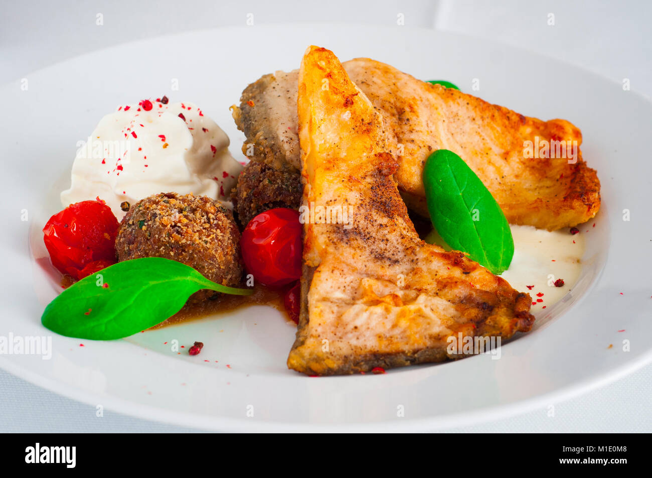 Gebratener Karpfen mit Tomaten Sahnesauce und Buchweizen Kugeln. Stockfoto