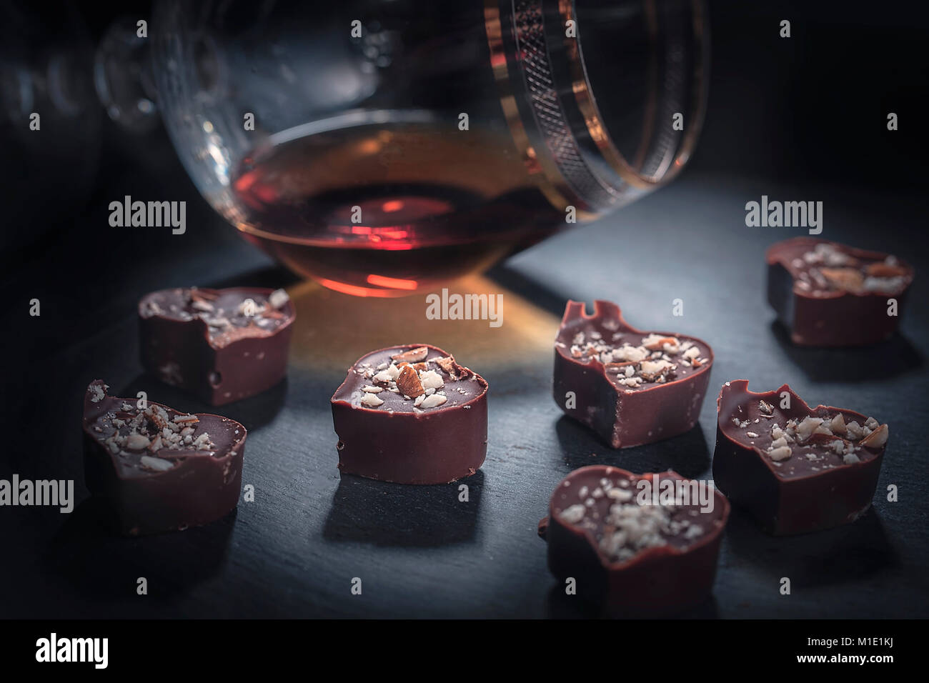 Schokolade in der Form eines Herzens fällt in ein Glas Brandy Horizontal Stockfoto