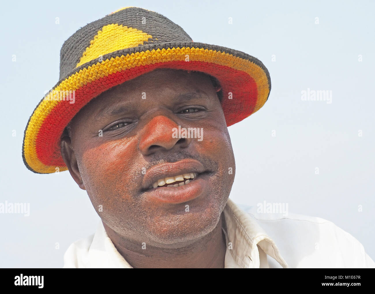 Mann mit Hut mit Uganda Flagge Farben bei Fischerdorf am Ufer des Lake Edward in Uganda Queen Elizabeth National Park. Stockfoto