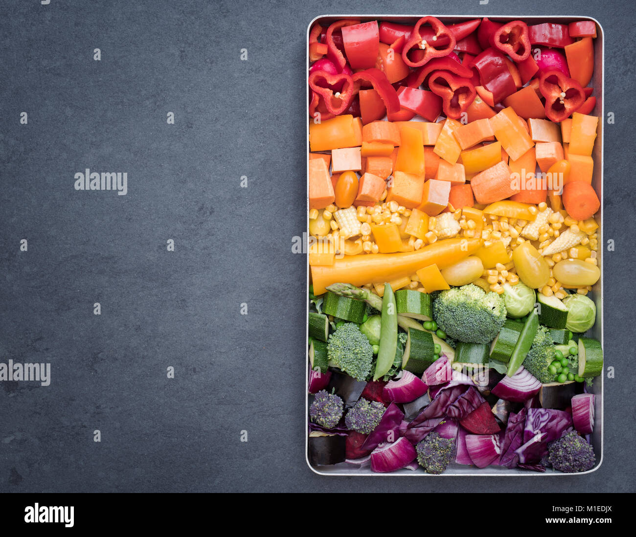 Schneiden bunte Gemüse in einem Backblech auf einer Schiefertafel Hintergrund Stockfoto