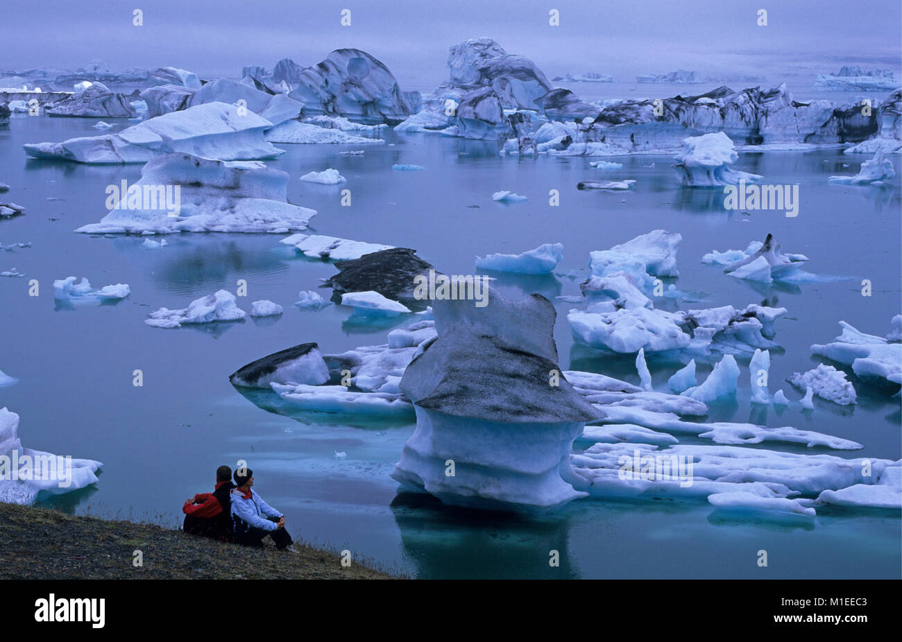Island. Jokulsarlon ist. Eisberge im See Jokulsarlon ist. Touristische Paar an Eisbergen. Stockfoto