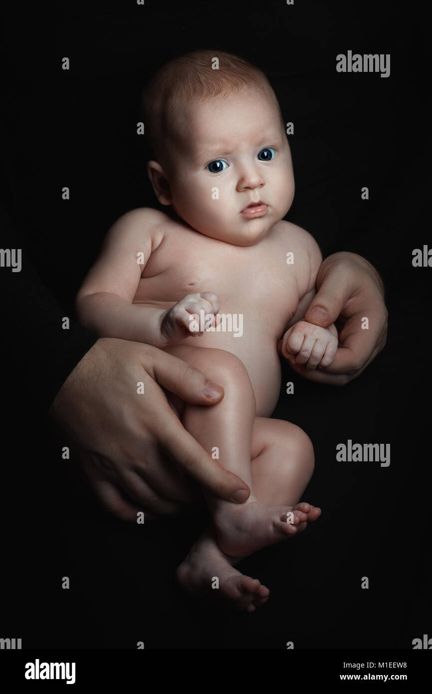 Männer Hände halten Baby Mädchen im Dunkeln. Stockfoto