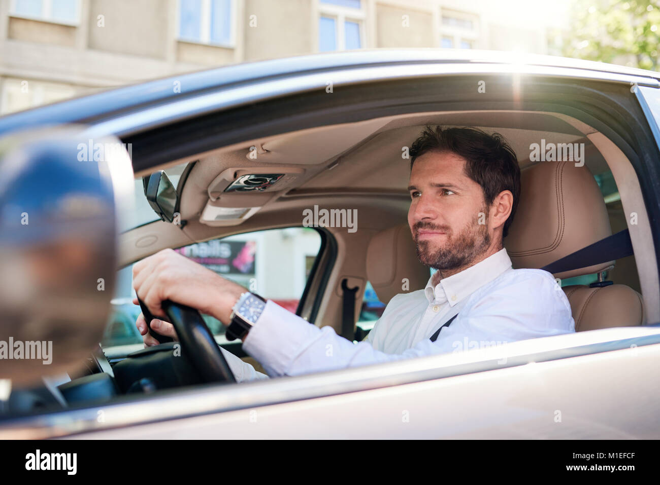 Lächelnden jungen Mann mit seinem Auto fährt während der morgendlichen Fahrt zum Arbeitsplatz Stockfoto