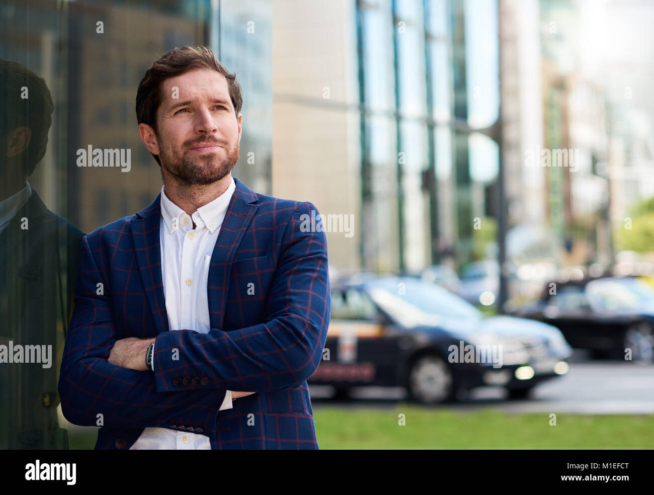 Erfolgreicher Geschäftsmann, der mit den Armen in der Stadt überschritten Stockfoto
