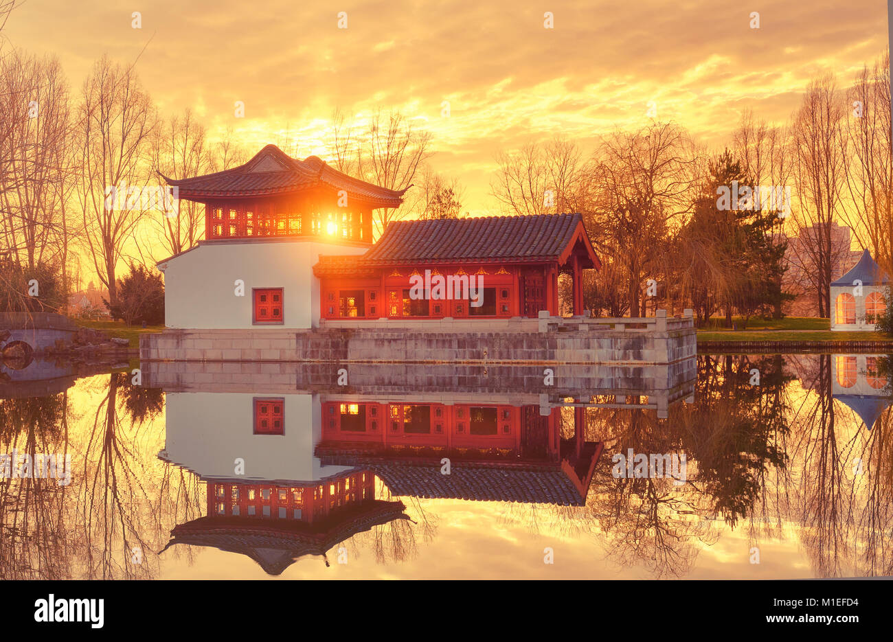 Winter Blick auf formellen Chinesischen Garten mit dekorativen Pavillon auf ein Sonnenuntergang mit Reflexion in den Teich. Stockfoto