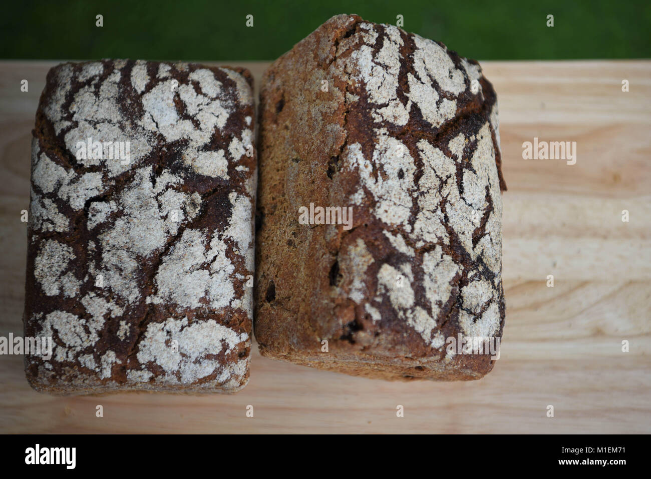 Essen von zu Hause Artisan Brot gewürzt mit Rosinen und Roggen für die dunkle Farbe und mit Mehl Muster oben auf einem urigen natürlichen Holz Schneidebrett Stockfoto
