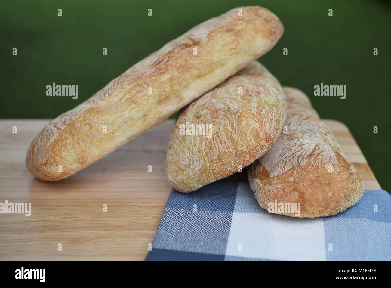 Rustikales essen Bild von hausgemachten artisan Ciabatta weißes Brot Brote auf Holzbrett mit grünem Gras Hintergrund für einen Sommer Picknick Einstellung Stockfoto
