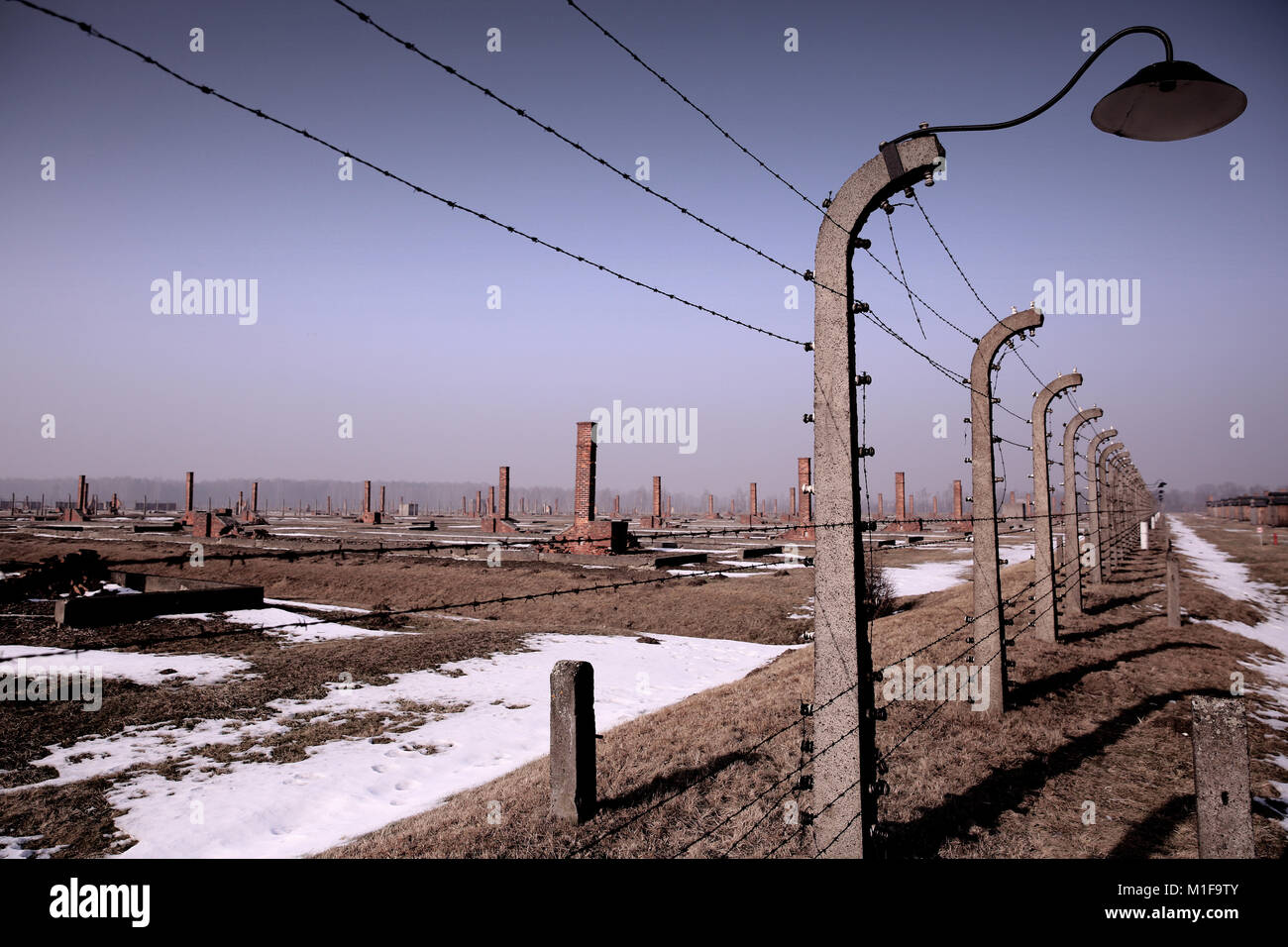 Elektrische fechten umliegenden Ruinen der zerstörten Holz- Unterkunft Hütten in Auschwitz II-Birkenau Holocaust Gedenkstätte und Museum. Red brick Schornsteine Stockfoto