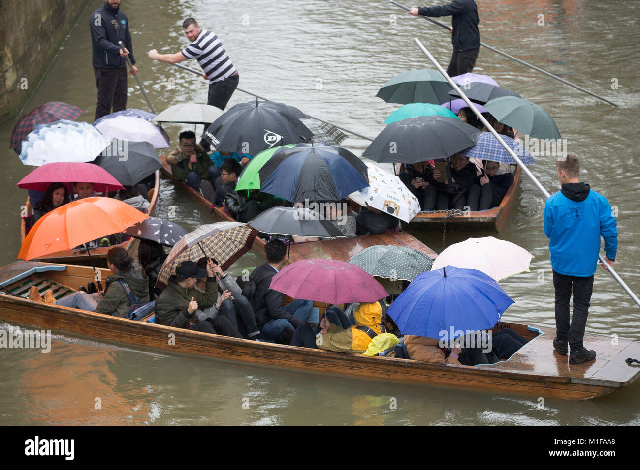 Touristen unter den Sonnenschirmen, während Sie stochern auf dem Fluss Cam in Cambridge, wie die sintflutartigen Regenfälle und starke Winde angekommen, wenn Sturm Georgina der Region getroffen. Stockfoto