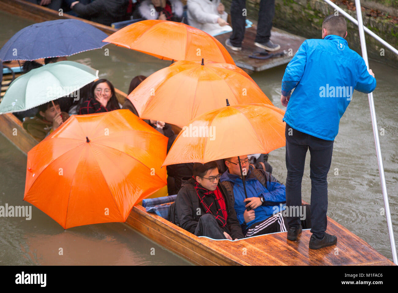 Touristen unter den Sonnenschirmen, während Sie stochern auf dem Fluss Cam in Cambridge, wie die sintflutartigen Regenfälle und starke Winde angekommen, wenn Sturm Georgina der Region getroffen. Stockfoto