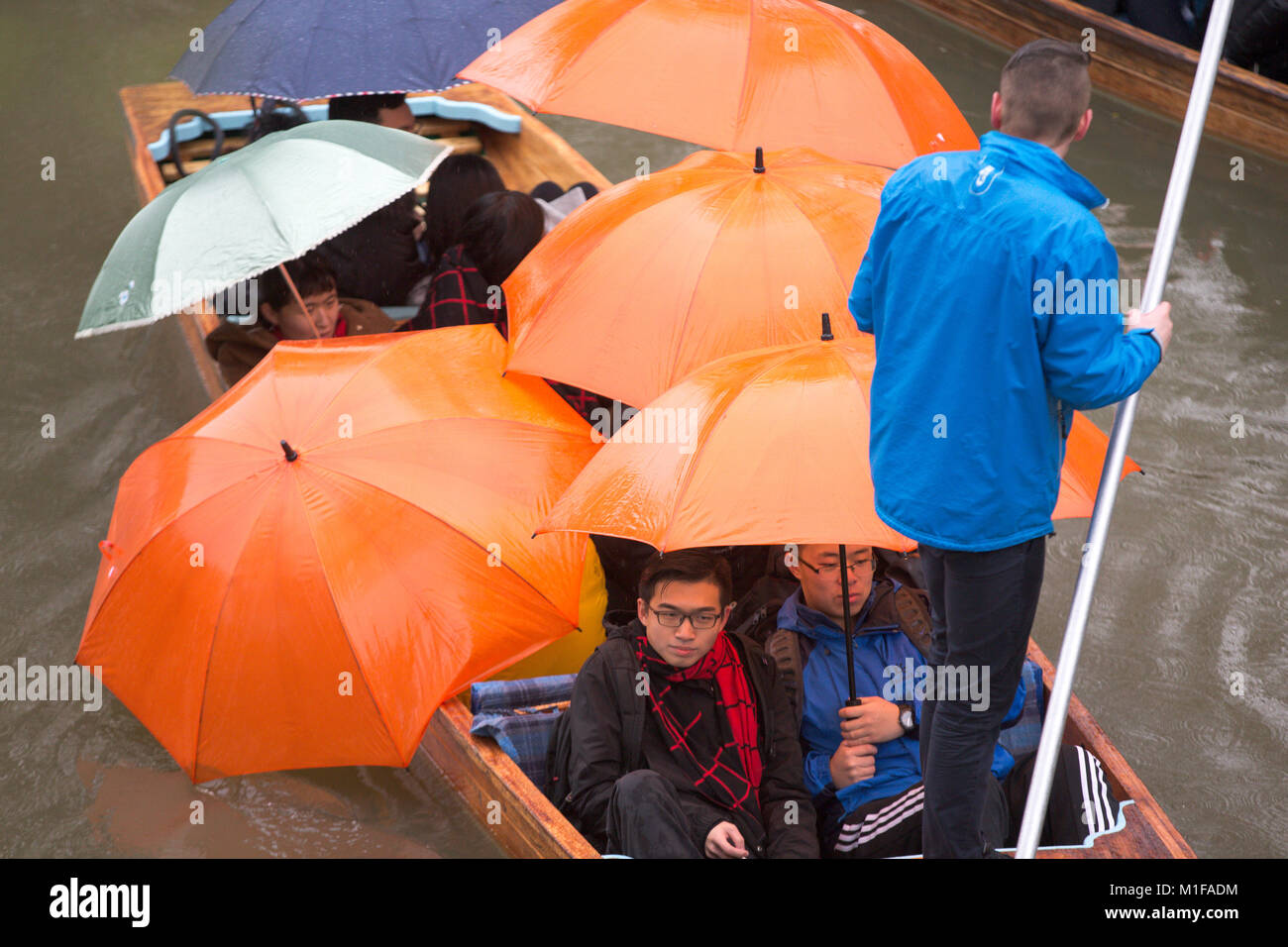 Touristen unter den Sonnenschirmen, während Sie stochern auf dem Fluss Cam in Cambridge, wie die sintflutartigen Regenfälle und starke Winde angekommen, wenn Sturm Georgina der Region getroffen. Stockfoto