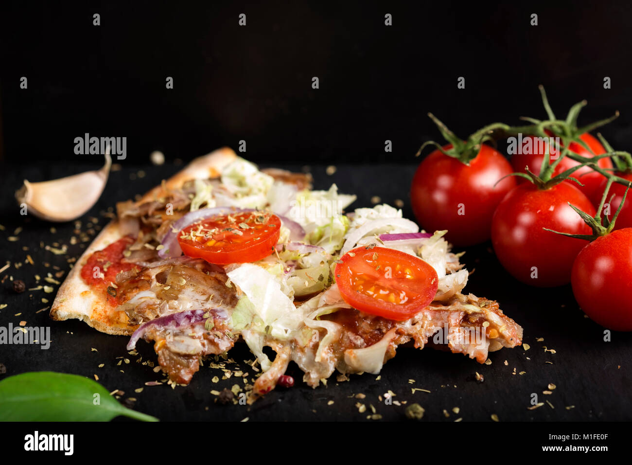Slace von kebap Pizza mit Hackfleisch, Kohl, Tomaten und getrockneten Oregano auf dunklem Schiefer Stockfoto