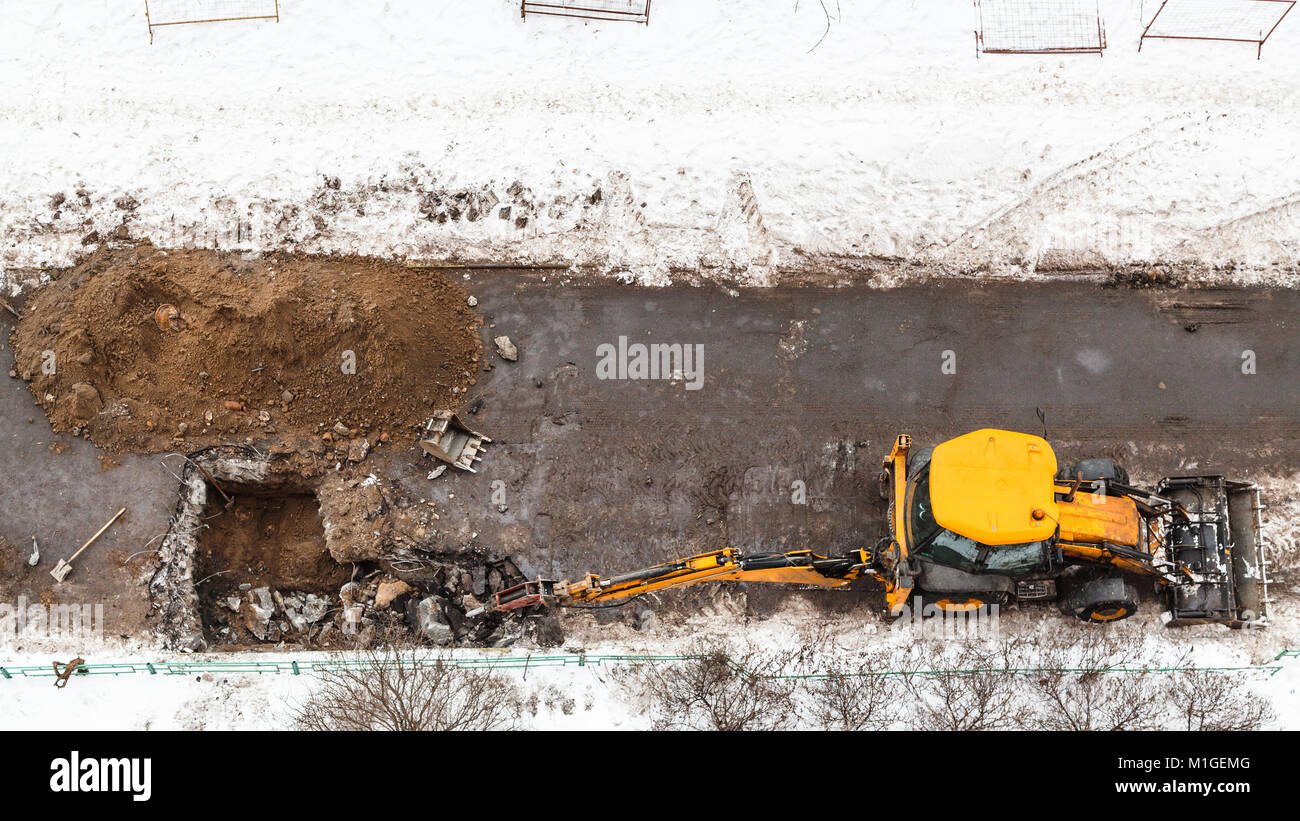 Oben Ansicht des Traktors graben Straße Kanalrohre im Winter in Moskau Stadt zu ändern. Stockfoto