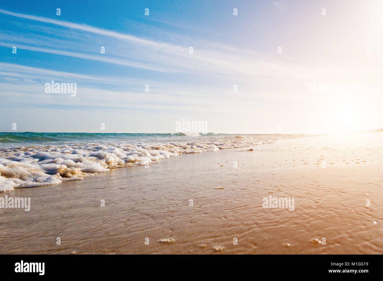 Ruhiges Meer und Surfen am Sandstrand. Sommer Meer bei sonnigem Wetter mit blauem Himmel. Schönen Sandstrand und transparente Wellen Stockfoto