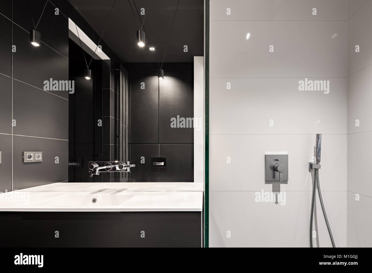 Badezimmer mit schwarzen Fliesen, Dusche, Waschbecken und Spiegel Stockfoto