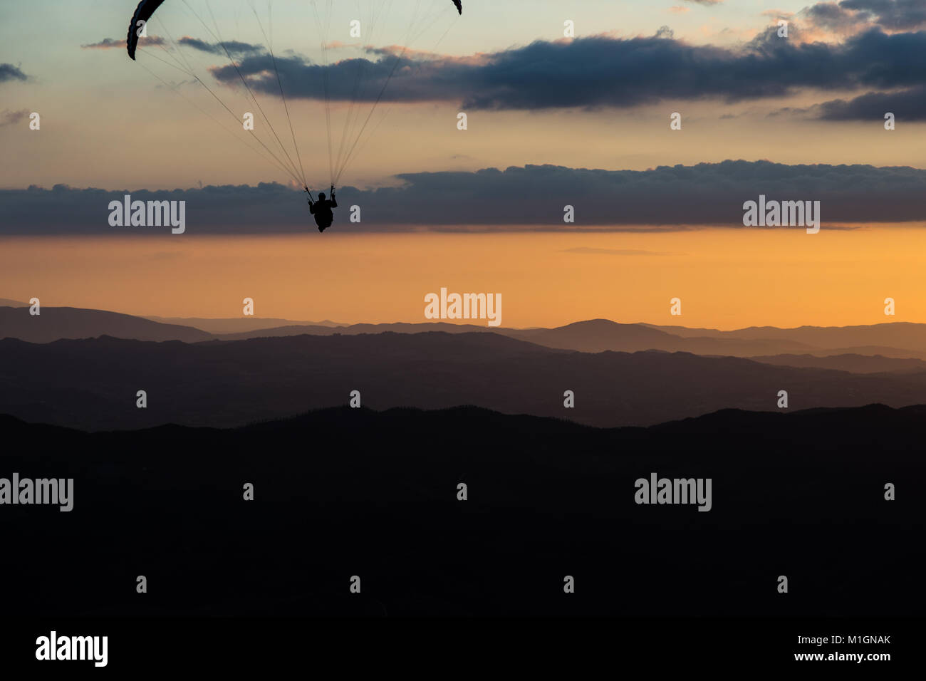 Schöne aufnahme eines Gleitschirms silhouette Fliegen über Monte Cucco (Umbrien, Italien) mit Sonnenuntergang im Hintergrund, mit schönen Farben und dunklen Töne Stockfoto