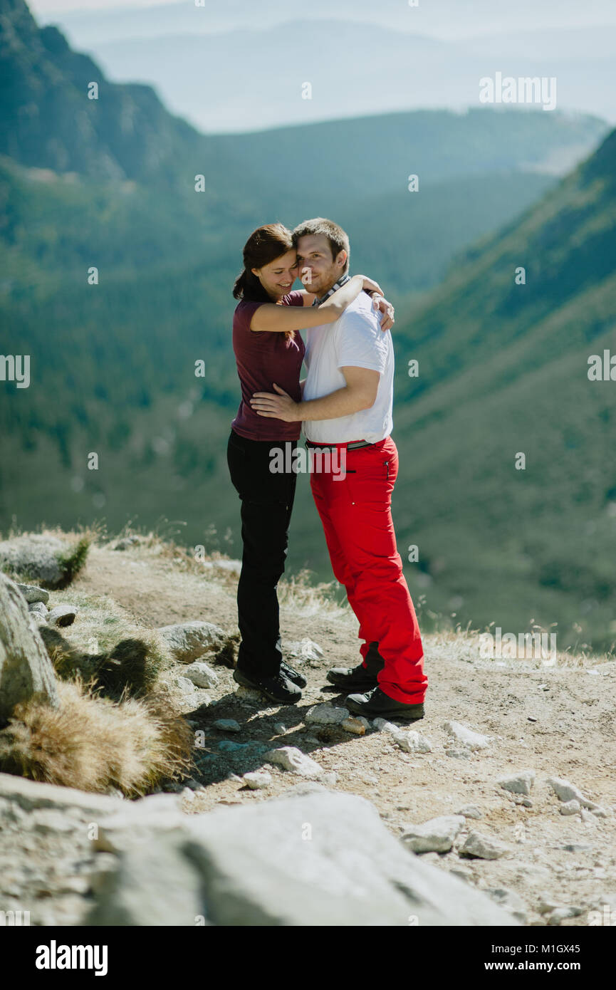 Mann und Frau in Liebe umarmen einander und genießen die Aussicht auf die Berge. Stockfoto