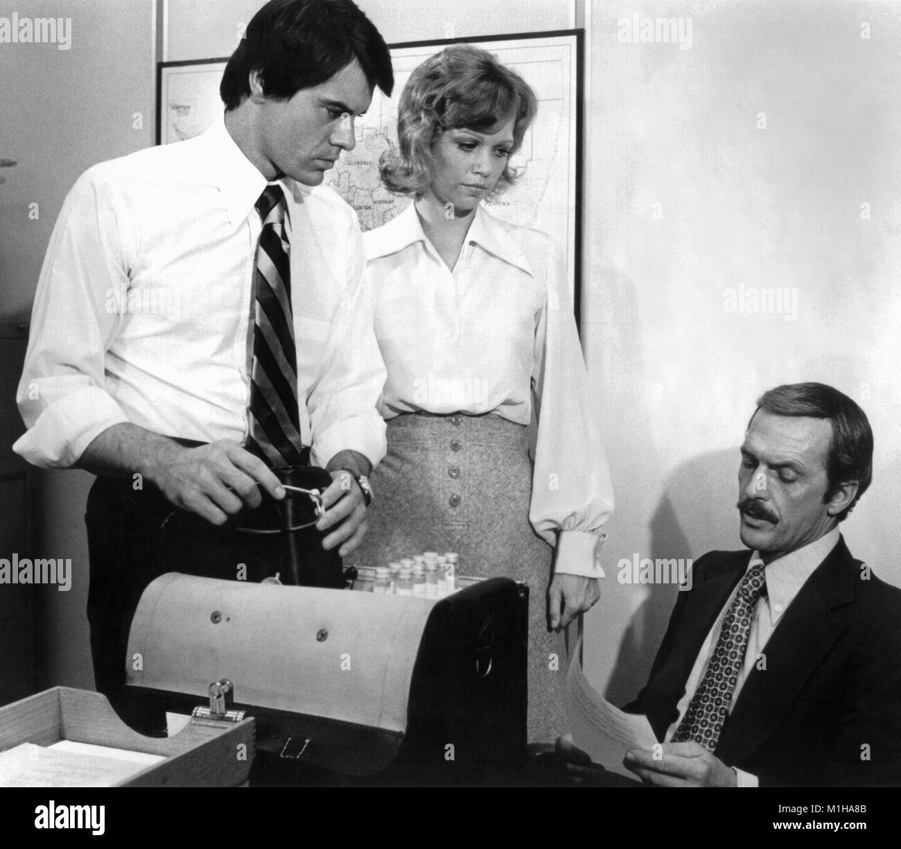 Werbung noch drei Schauspieler zeigen, Robert Urich, Maureen Reagan und Jack Hogan, am Set Posing, in einem Büro/Labor mit einer Tasche voller Reagenzgläser, während der Dreharbeiten zu dem TV-Pilot mit dem Titel "Der Spezialist", die empfohlene fiktive Beamte des öffentlichen Gesundheitswesens und wurde nicht als Serie, 1974 abgeholt. Mit freundlicher CDC. () Stockfoto