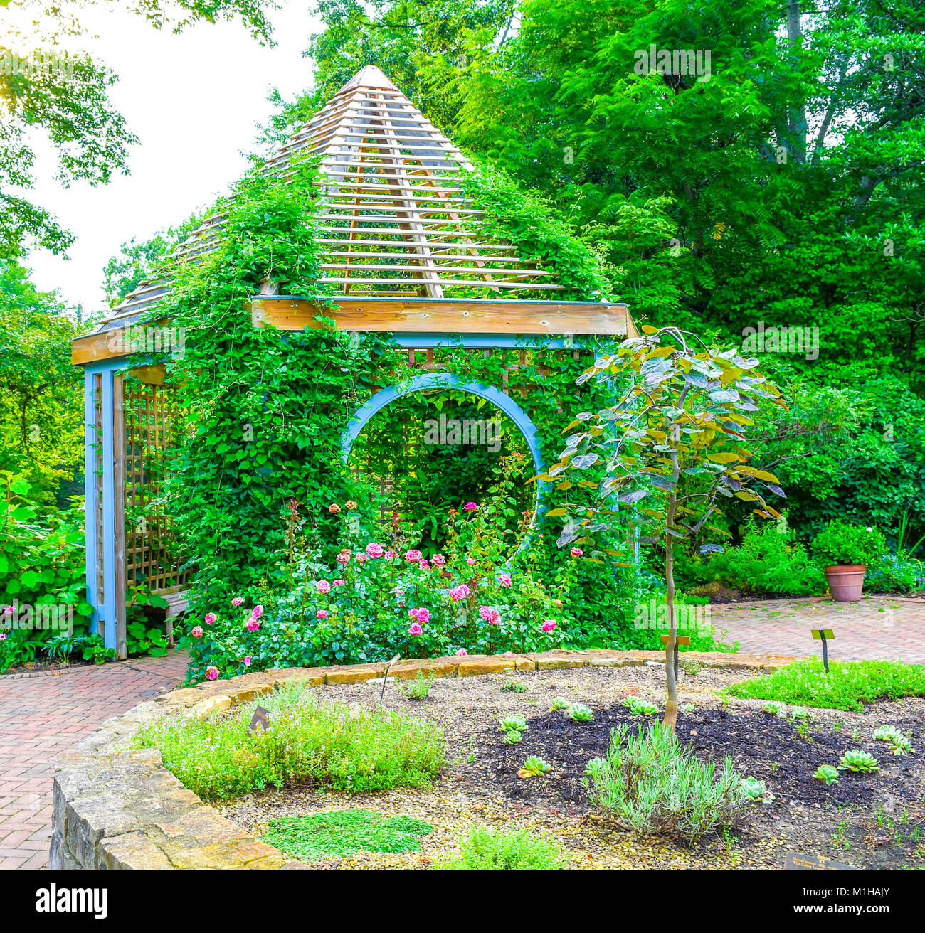 In der Mitte von einem schönen Garten befindet sich ein Pavillon. Üppige Landschaft umgibt den Garten. Stockfoto