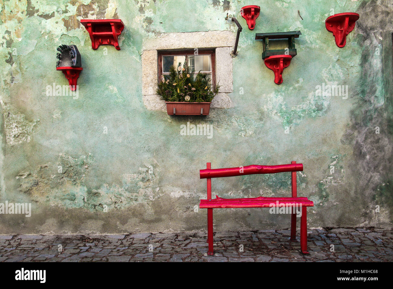 Eine schöne und ruhige Ecke mit einer roten Bank aus Holz, Fenster mit den Winter Dekoration und rote Regale mit Blumentöpfen. Stockfoto