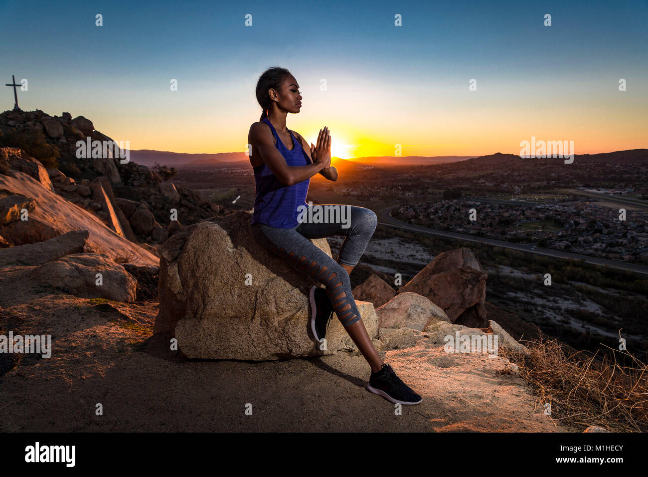 Junge afrikanische amerikanische Frau meditiert auf einem Berg bei einem Sonnenuntergang in Kalifornien. Foto von Francis Specker Stockfoto