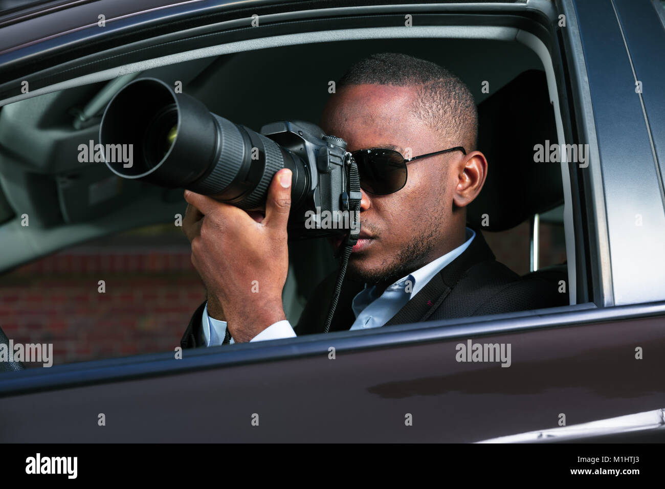 Privatdetektiv Sitzen im Auto Fotografieren mit SLR-Kamera Stockfoto