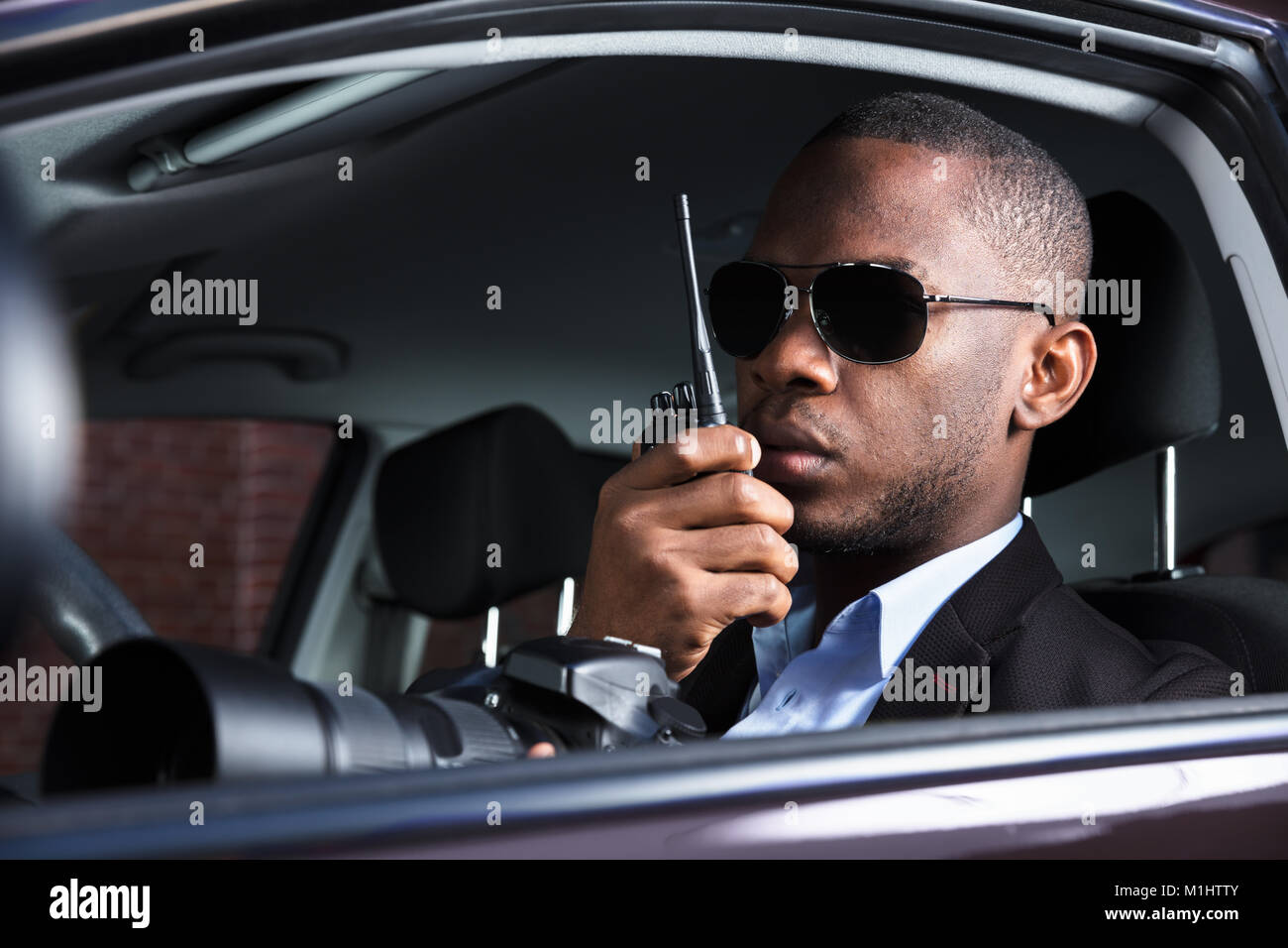 Privatdetektiv Sitzen im Auto Holding Spiegelreflexkamera und Walkie Talkie Stockfoto