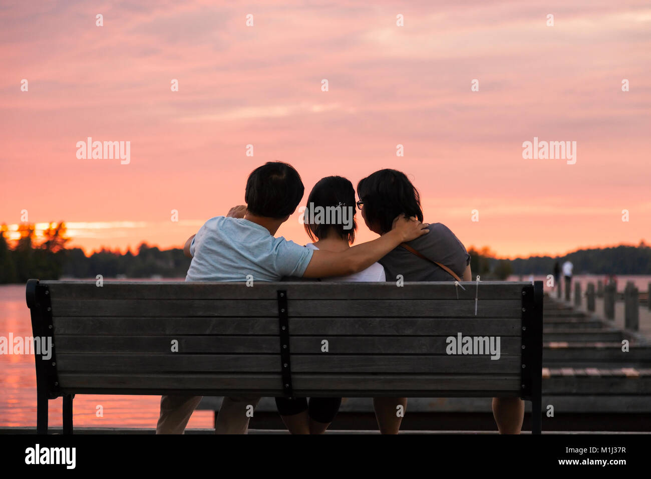 Menschen, die auf einer Bank sitzen genießen den Sonnenuntergang am Muskoka Wharf in Gravenhurst MUSKOKA, Ontario, Kanada. Stockfoto