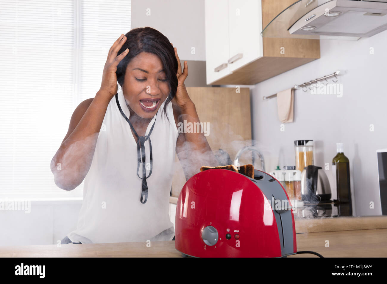 Frustriert Afrikanische junge Frau bei Burnt Toast aus der Toaster in der Küche Stockfoto