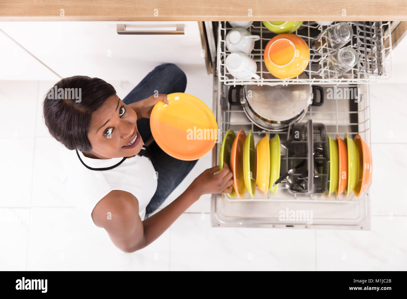 Lächelnde Junge afrikanische Frau, die die Platten in der Spülmaschine Stockfoto