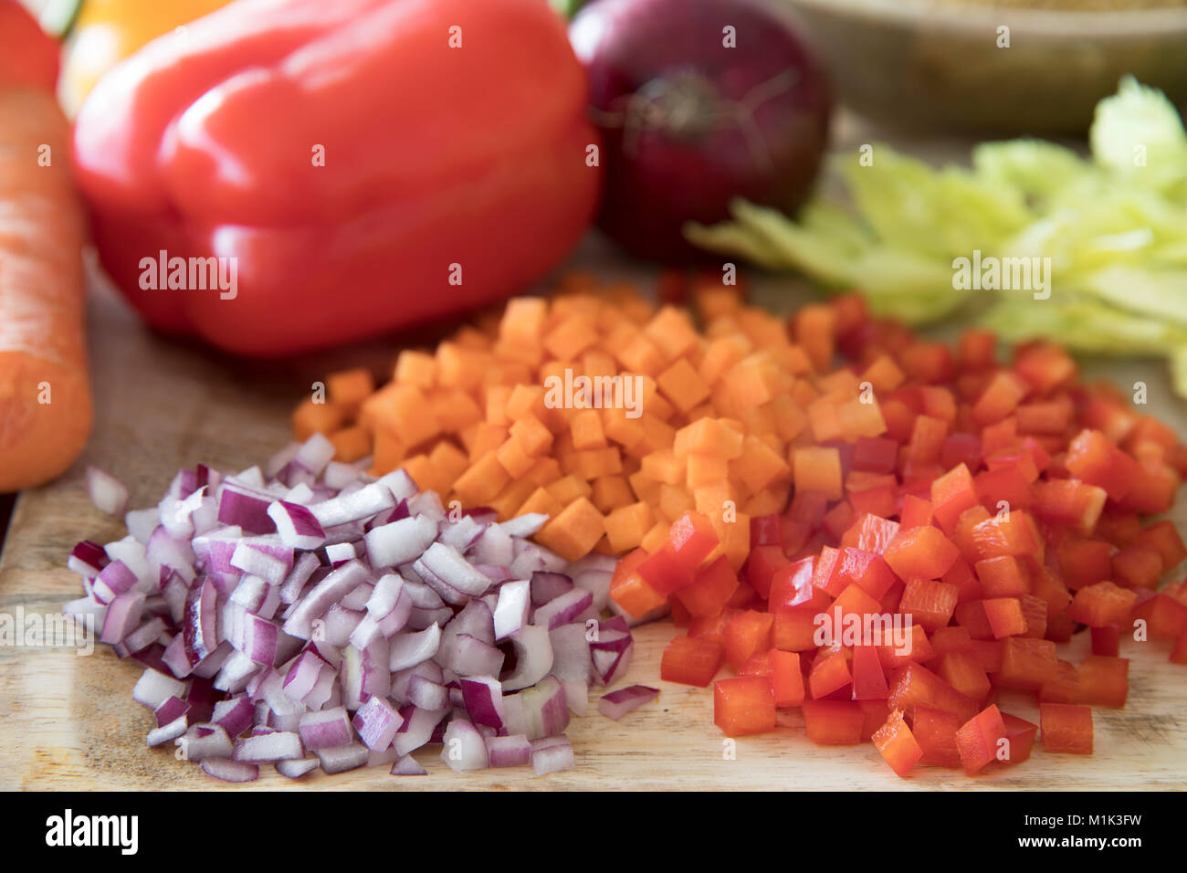 Red Paprika, Karotten und Zwiebeln gewürfelt auf einem Schneidebrett. Stockfoto