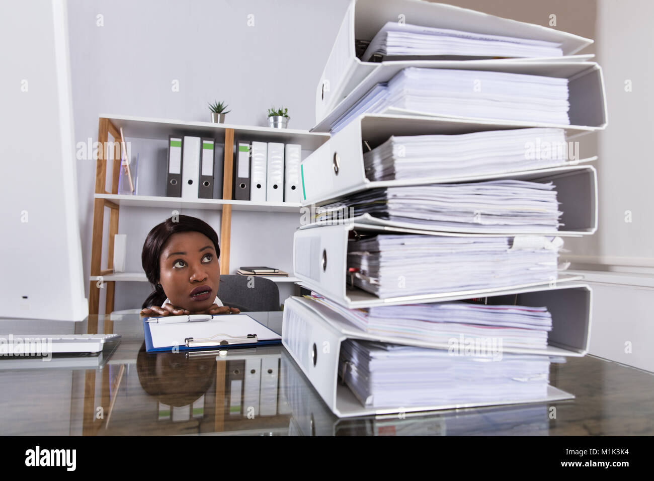Junge afrikanische Frau Suchen auf Stapel von Ordnern auf dem Schreibtisch im Büro Stockfoto