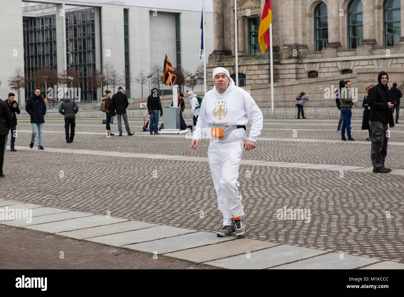 Man Joggen vor dem Reichstag in weißen Trainingsanzug mit deutschen Wappen Eagle Crest auf dem Sweatshirt graviert und spielen Radio Stockfoto