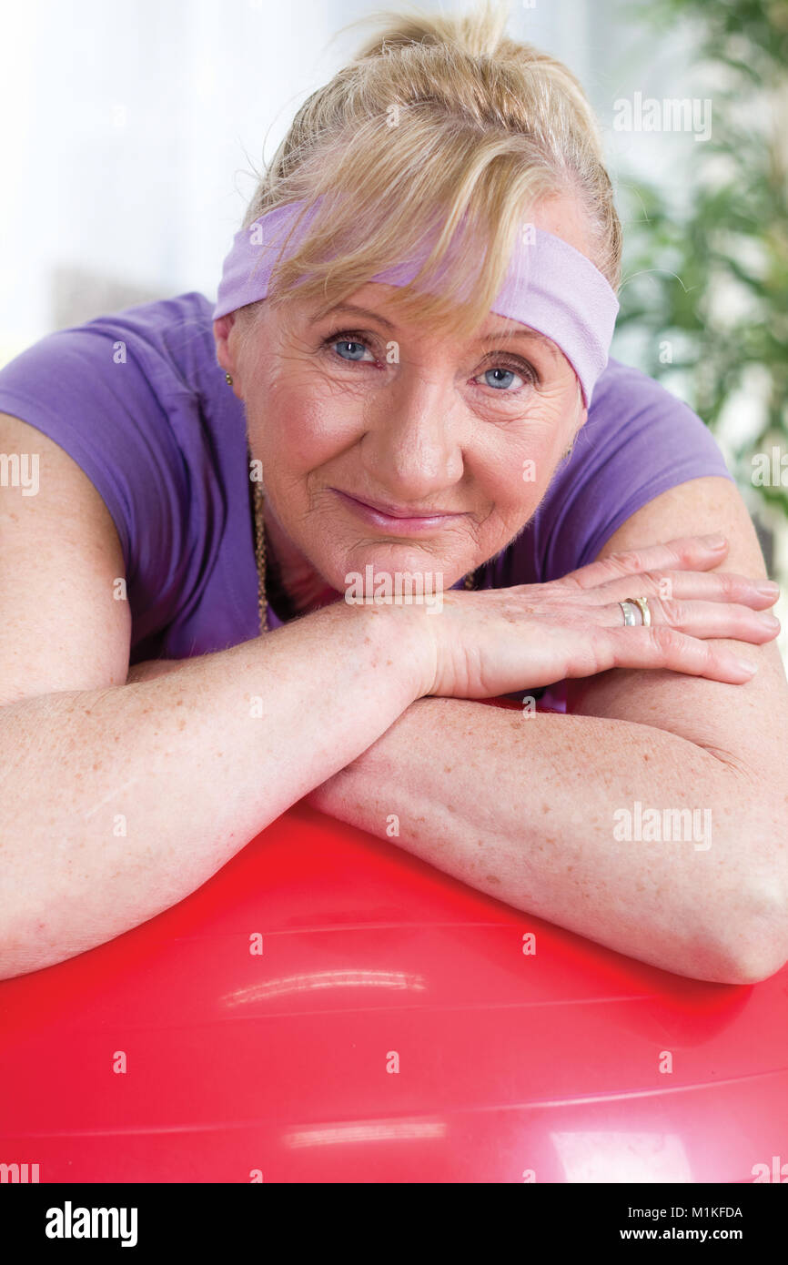 Ältere Frau ausruhen nach Übungen in roten Gymnastikball Stockfoto