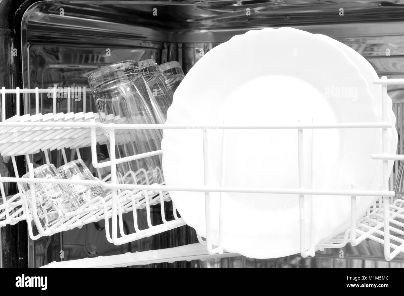 Oberen Korb mit frisch gewaschenen Untertassen und einige Gläser in die Spülmaschine Stockfoto