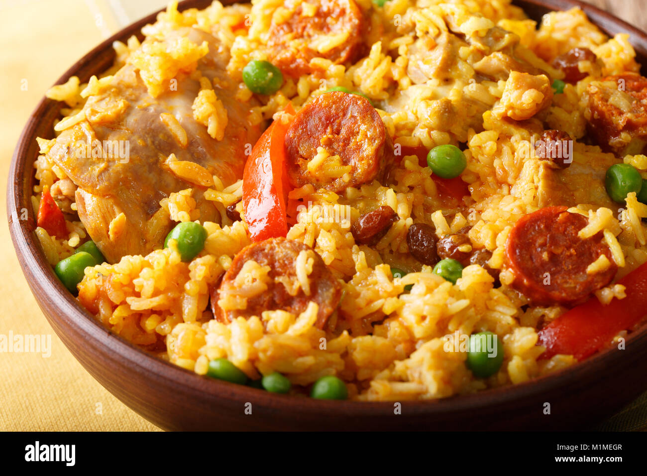 Köstliche Arroz Valenciana mit Reis, Fleisch, Wurst, Chorizo, Gemüse und Gewürze in der Nähe in einer Schüssel auf dem Tisch. Horizontale Stockfoto