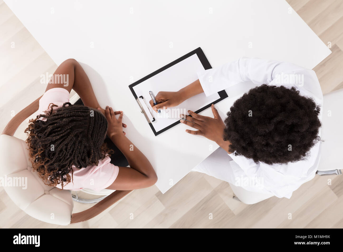 Hohe Betrachtungswinkel von Arzt und Patient Sitzen in Klinik mit Zwischenablage Stockfoto